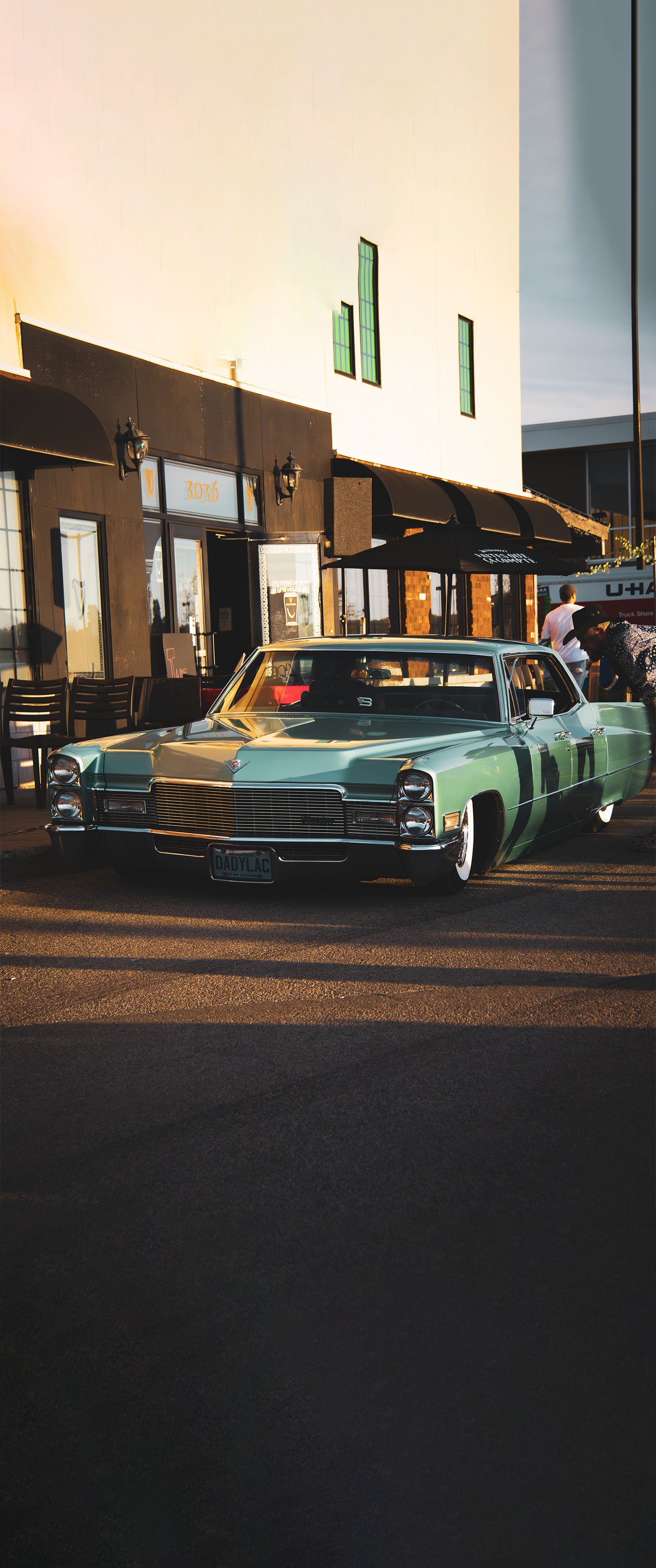 Photo of an old cadilac infront of a building at noon