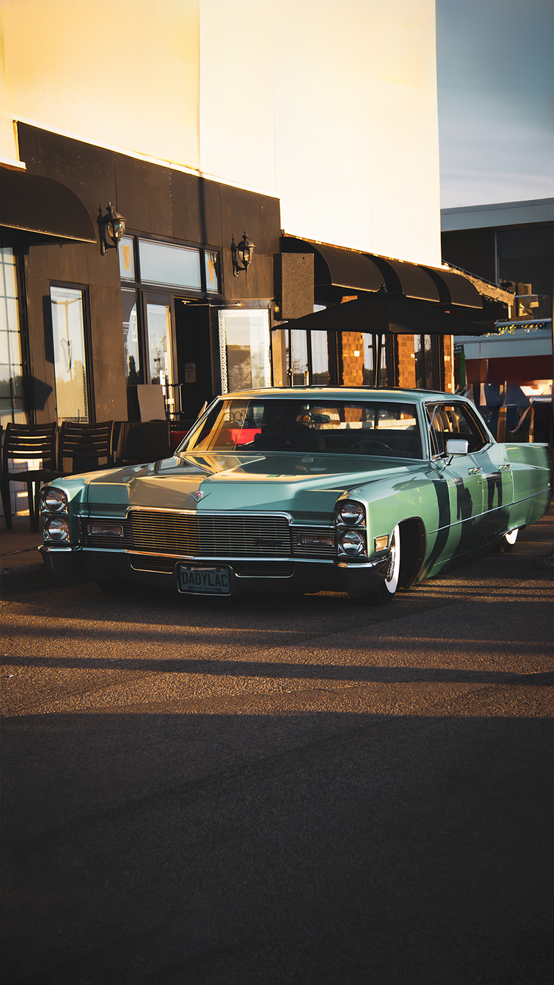 Photo of an old blue cadilac infront of a building