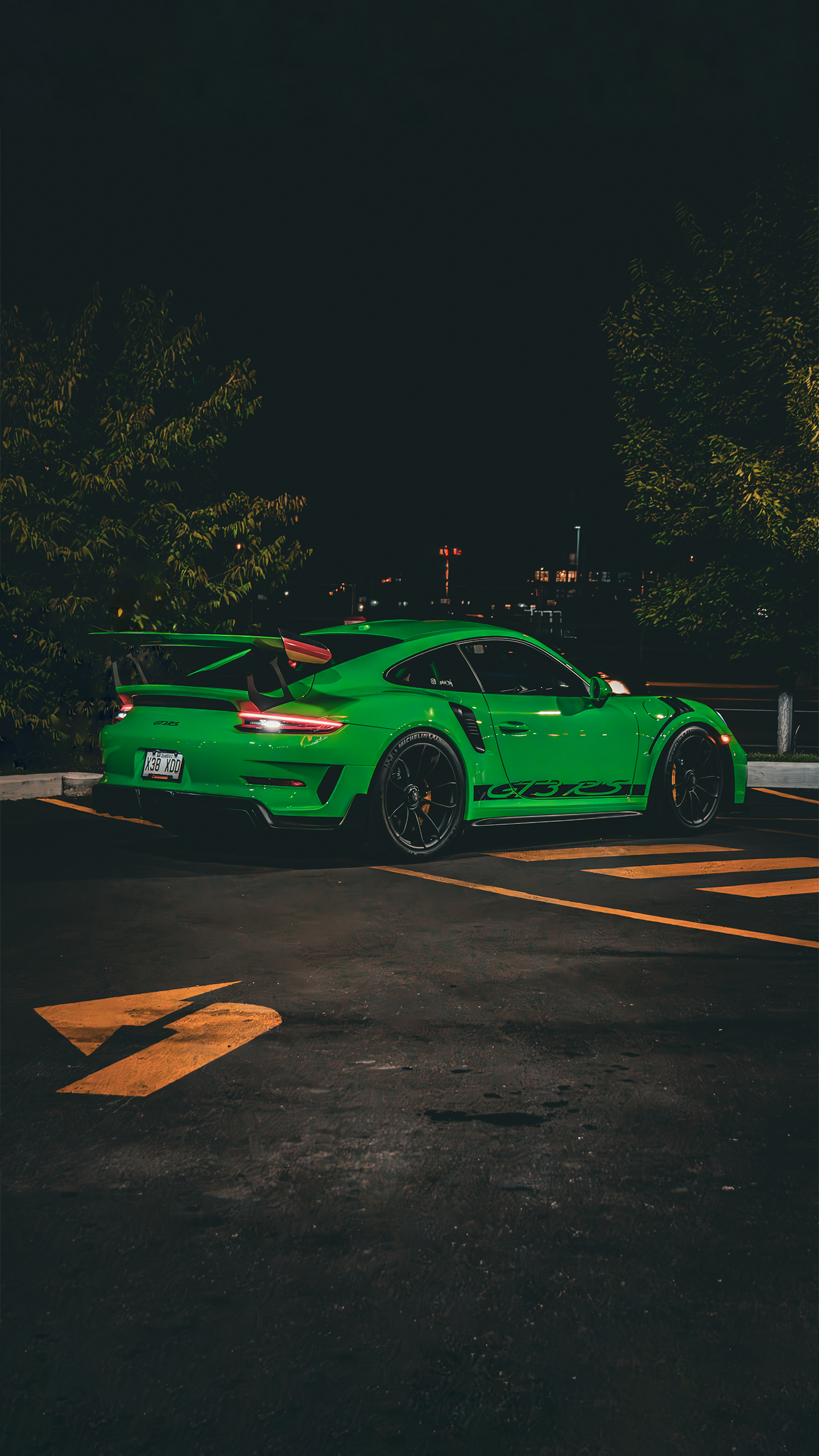 Photo of a Green Porsche GT3RS at night infront of bushes